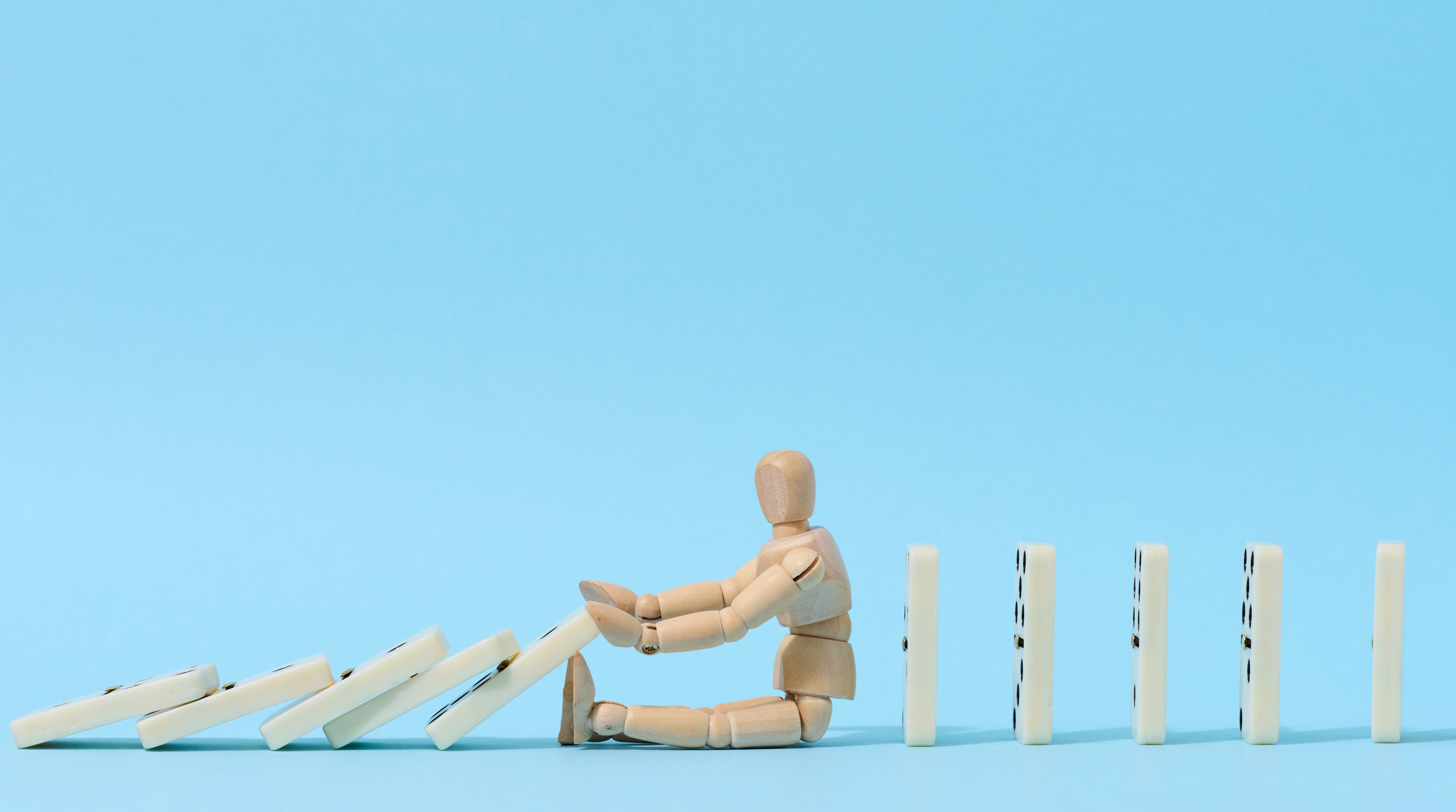 a wooden man is sitting on top of dominoes on a blue background