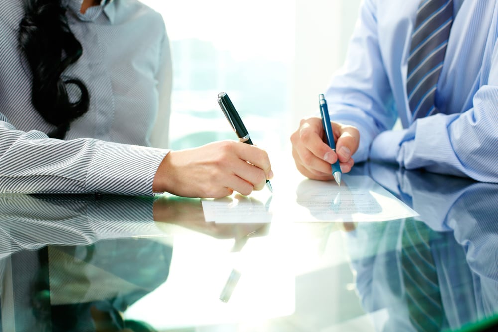 two people sitting at a table with a pen and paper